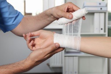 Photo of Doctor applying bandage onto patient's wrist in hospital, closeup