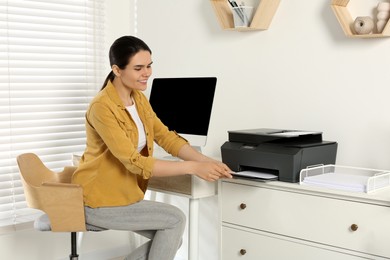 Photo of Woman using modern printer at workplace indoors