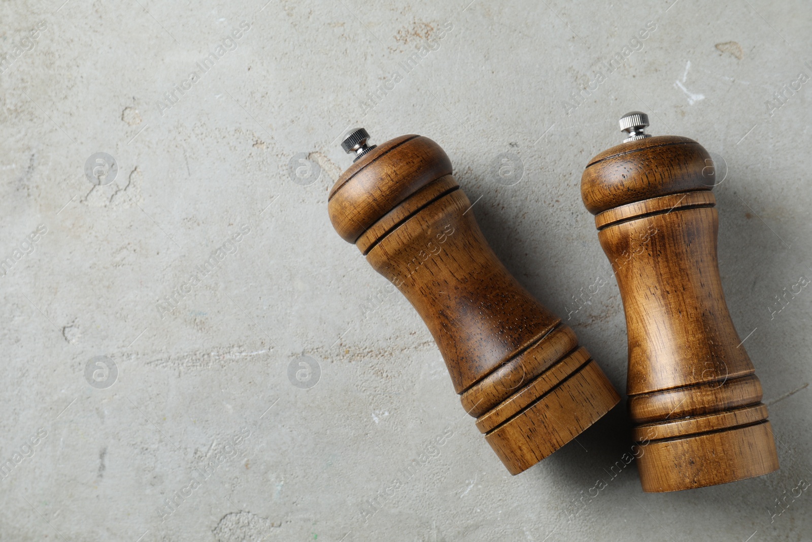 Photo of Wooden salt and pepper shakers on light textured table, top view. Space for text