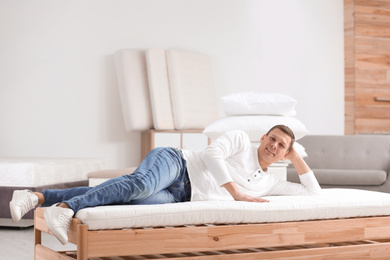 Photo of Man testing soft mattress in furniture store