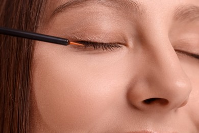 Photo of Woman applying serum onto eyelashes, closeup view