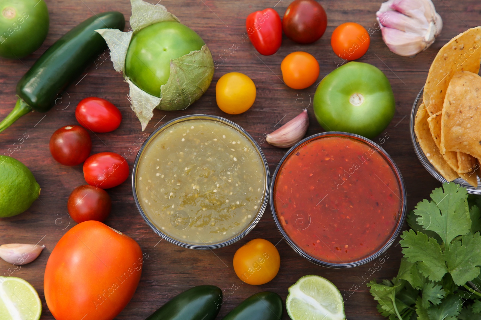 Photo of Flat lay composition of tasty salsa sauces and different ingredients on wooden table