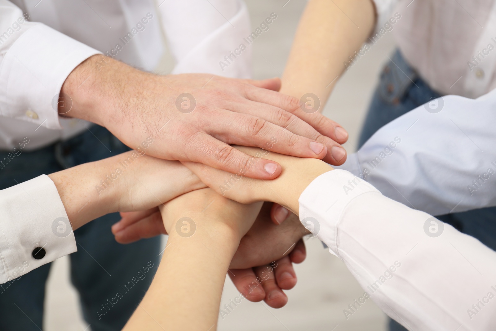 Photo of People holding hands together in office, closeup