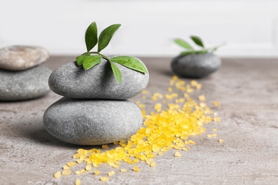 Photo of Spa stones, sea salt and leaves on grey table. Space for text