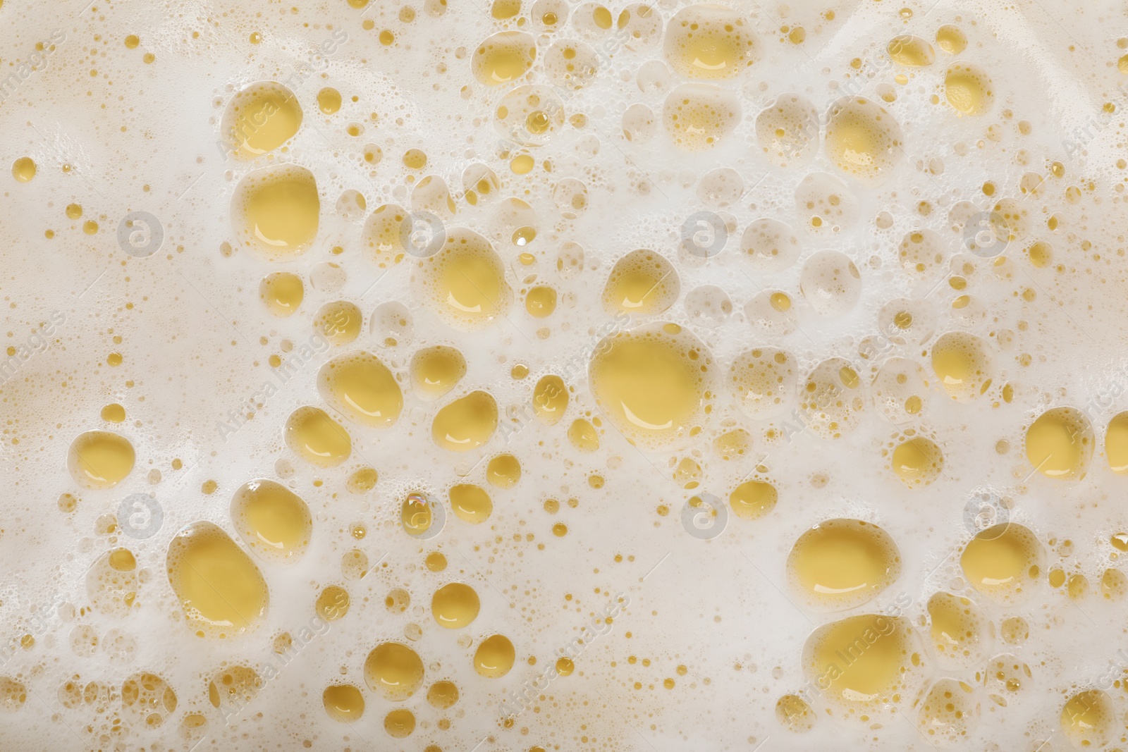 Photo of White washing foam on yellow background, top view