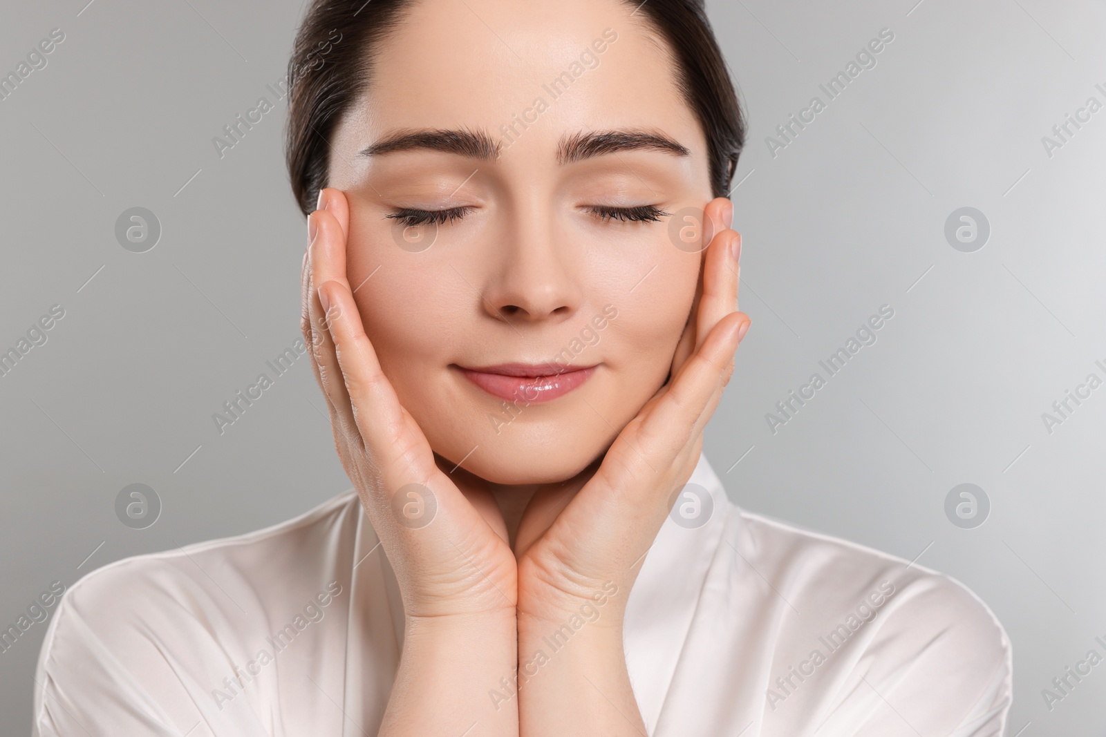 Photo of Young woman massaging her face on grey background