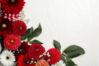Flat lay composition with beautiful dahlia flowers on white wooden background. Space for text