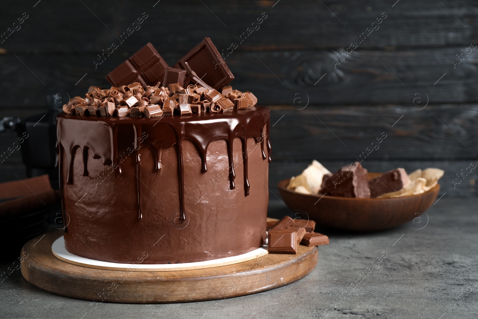 Photo of Freshly made delicious chocolate cake on grey table against black background. Space for text