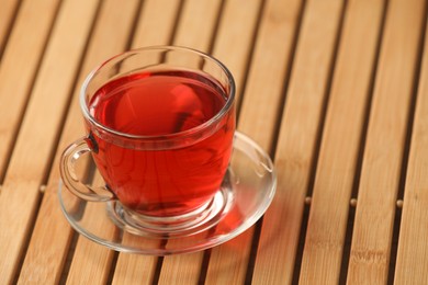 Cup of delicious hibiscus tea on wooden table, space for text