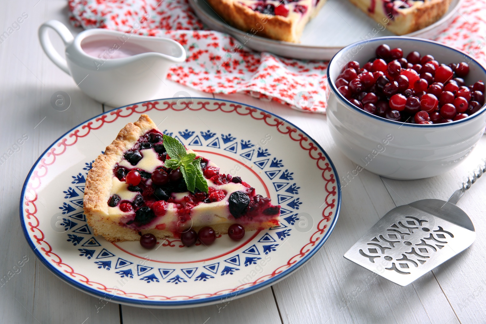 Photo of Piece of delicious currant pie served on white wooden table