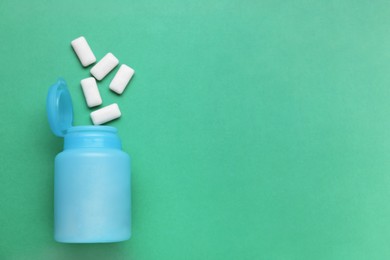 Jar with chewing gums on green background, flat lay. Space for text