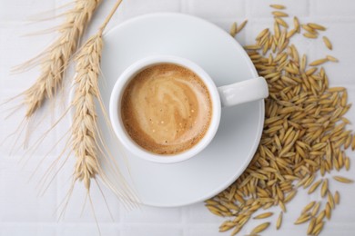 Photo of Cup of barley coffee, grains and spikes on white table, flat lay
