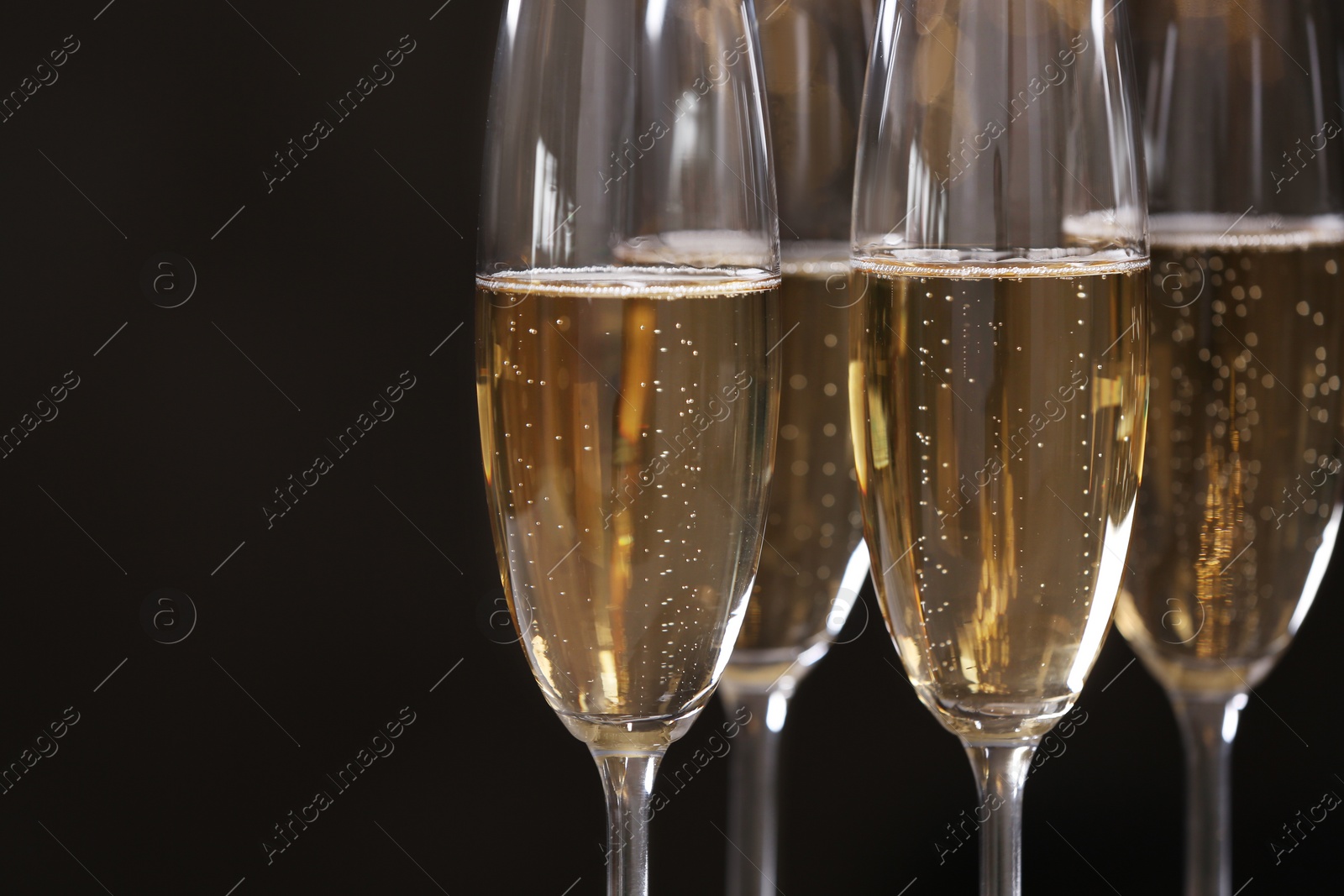 Photo of Glasses of champagne on dark background, closeup. Space for text