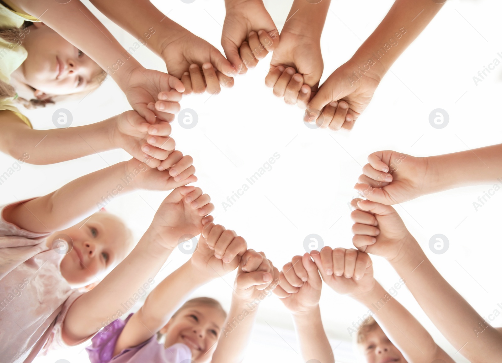 Photo of Little children putting their hands together indoors, view from below. Unity concept