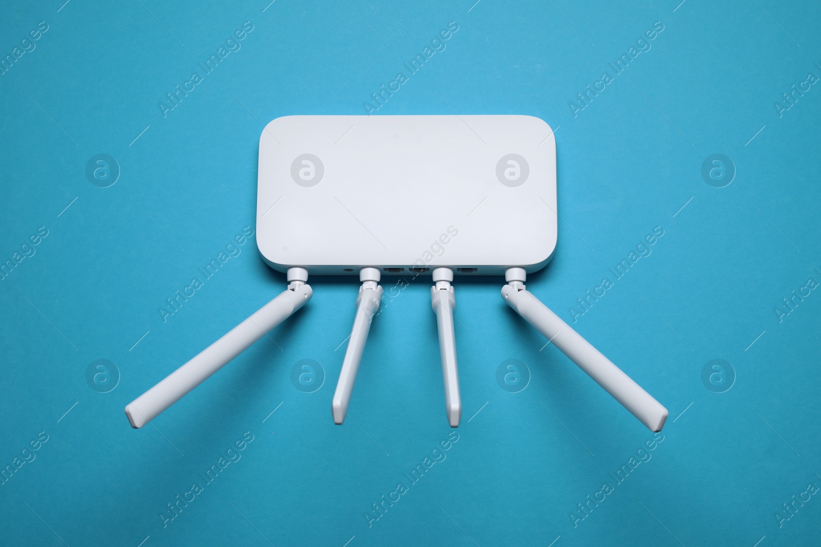 Photo of New white Wi-Fi router on light blue background, top view