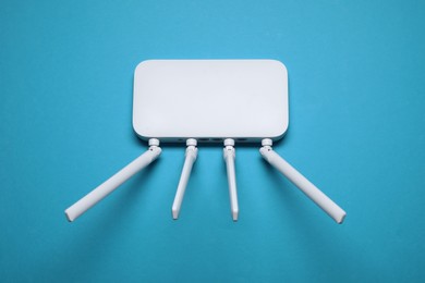 New white Wi-Fi router on light blue background, top view