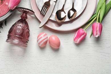 Festive Easter table setting with eggs on wooden background, top view