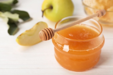 Photo of Jar of honey, apples and dipper on wooden table