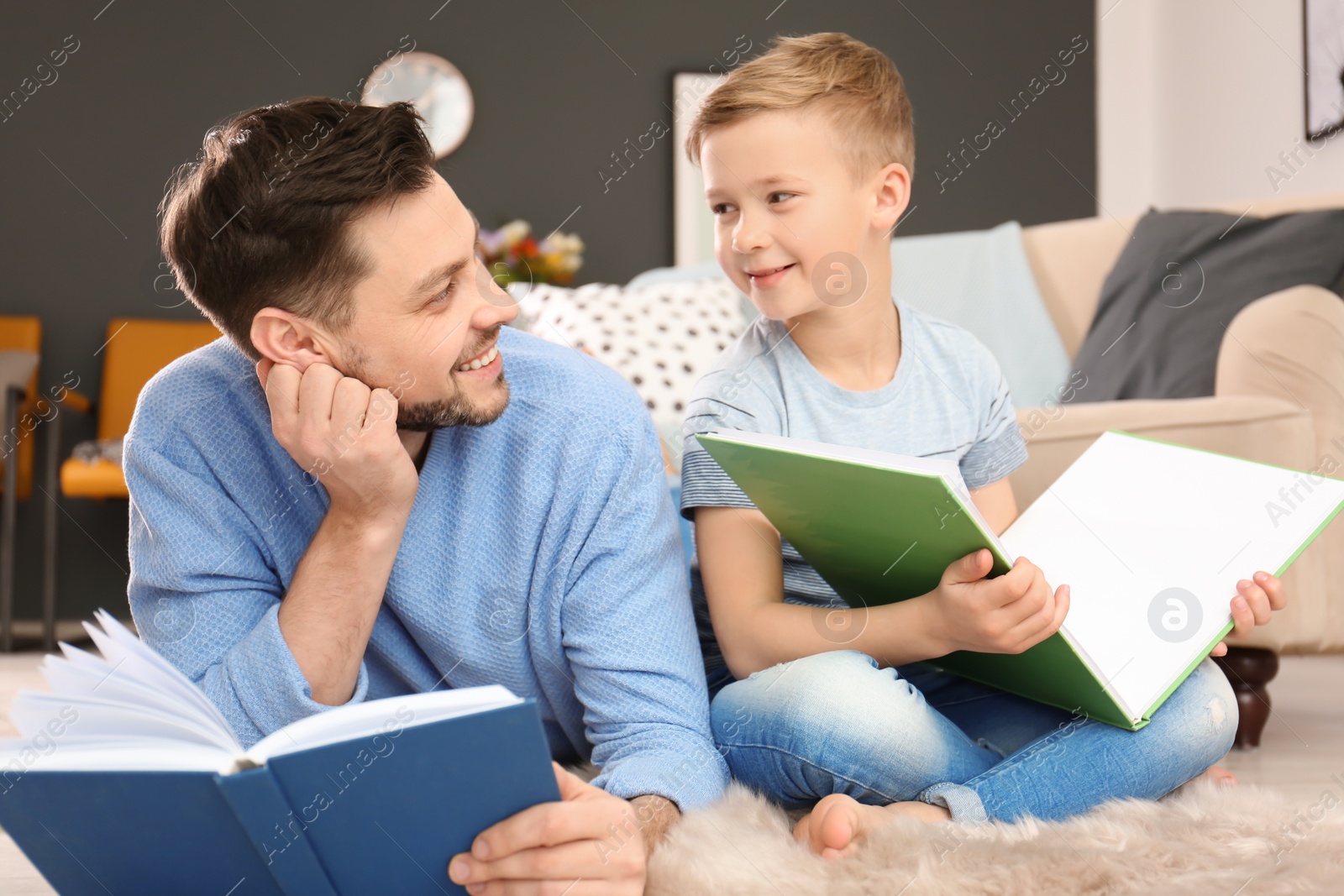 Photo of Little boy and his dad reading books at home