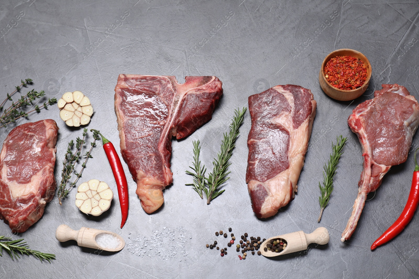 Photo of Fresh raw beef cuts and different spices on light grey textured table, flat lay