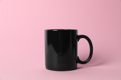 Photo of One black ceramic mug on pink background