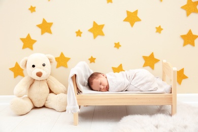 Adorable newborn baby sleeping in small bed
