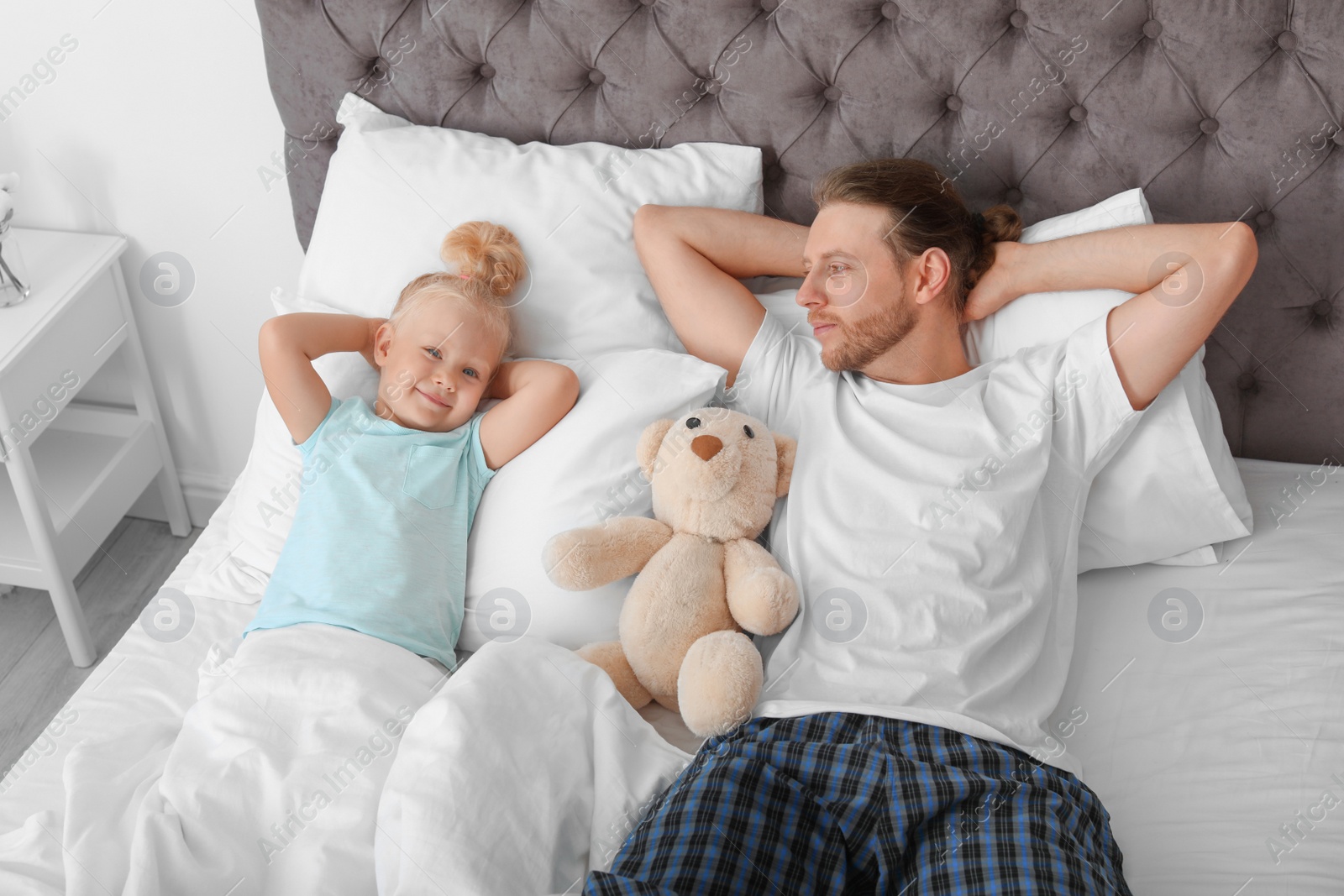 Photo of Cute little girl with her father in bed. Sleeping time