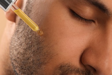 Photo of Man applying cosmetic serum onto face, closeup