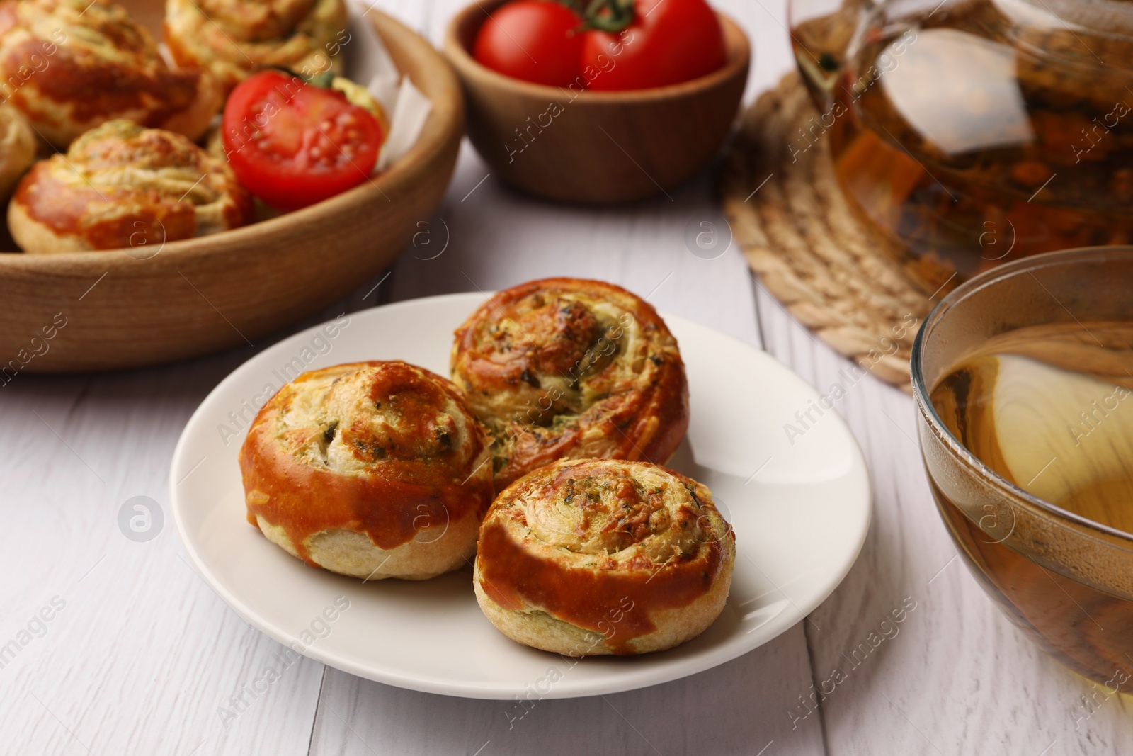 Photo of Fresh delicious puff pastry served with tea on white wooden table, closeup