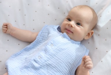 Photo of Cute little baby lying in crib at home, top view