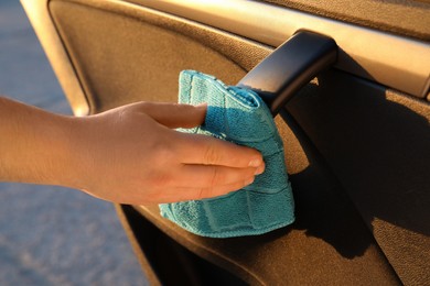 Photo of Man with duster sanitizing car door handle outdoors, closeup