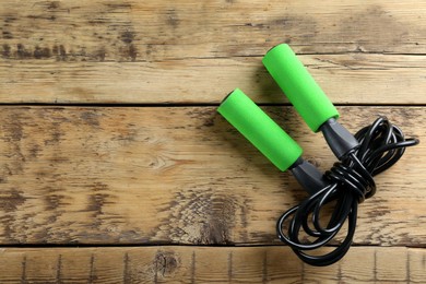 Photo of Skipping rope on wooden table, top view. Space for text