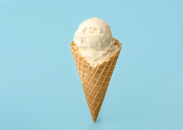 Delicious ice cream in waffle cone on light blue background