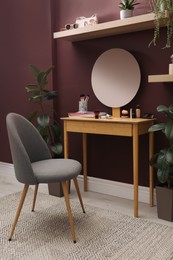 Photo of Wooden dressing table and chair near brown wall in room