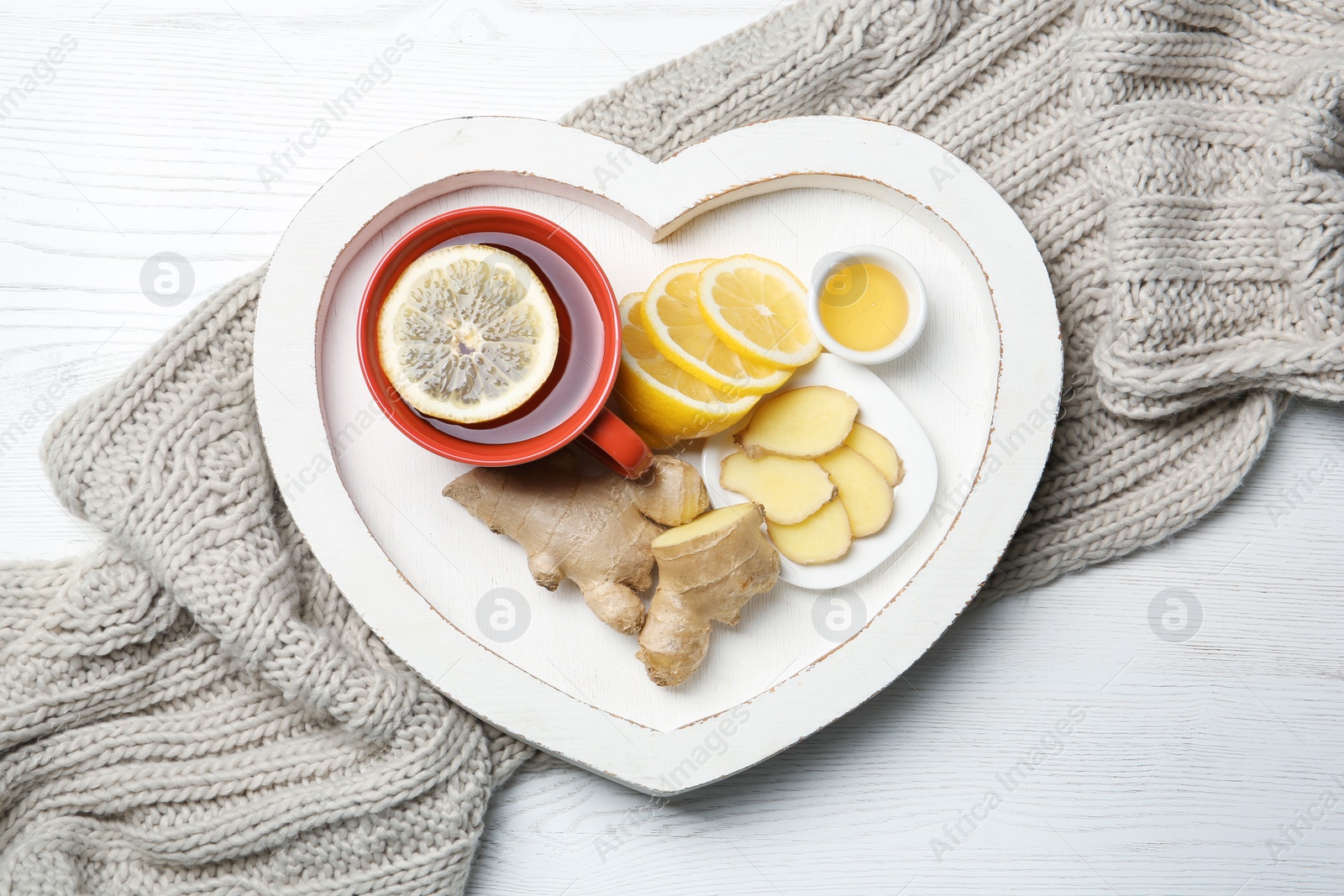 Photo of Heart shaped tray with lemon ginger tea on wooden background, flat lay