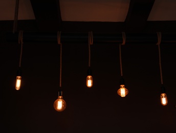 Glowing lamp bulbs in dark room. Interior element