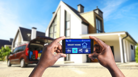 Image of African-American man using home security app on smartphone outdoors, closeup