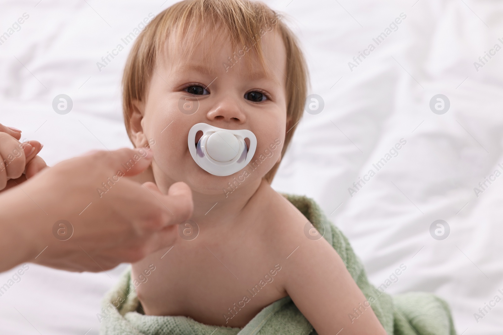 Photo of Mother wrapping her cute little baby with towel after bathing on bed