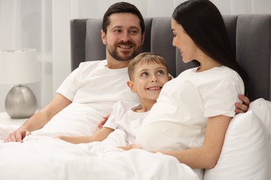 Pregnant woman with her son and husband in bed at home. Happy family