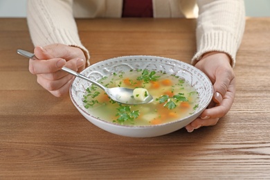 Sick woman eating fresh homemade soup to cure flu at table, closeup
