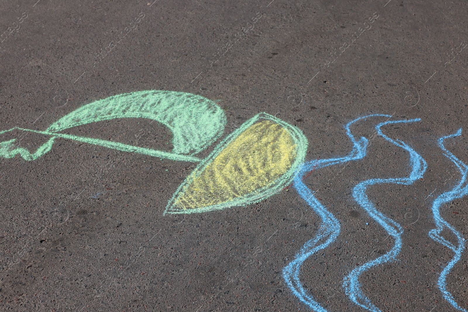 Photo of Child's chalk drawing of boat on asphalt