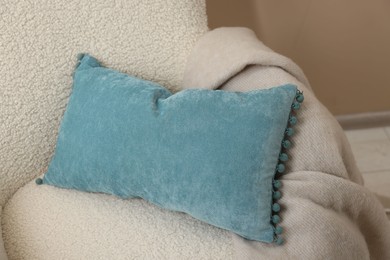 Photo of Soft blue pillow and blanket on armchair indoors