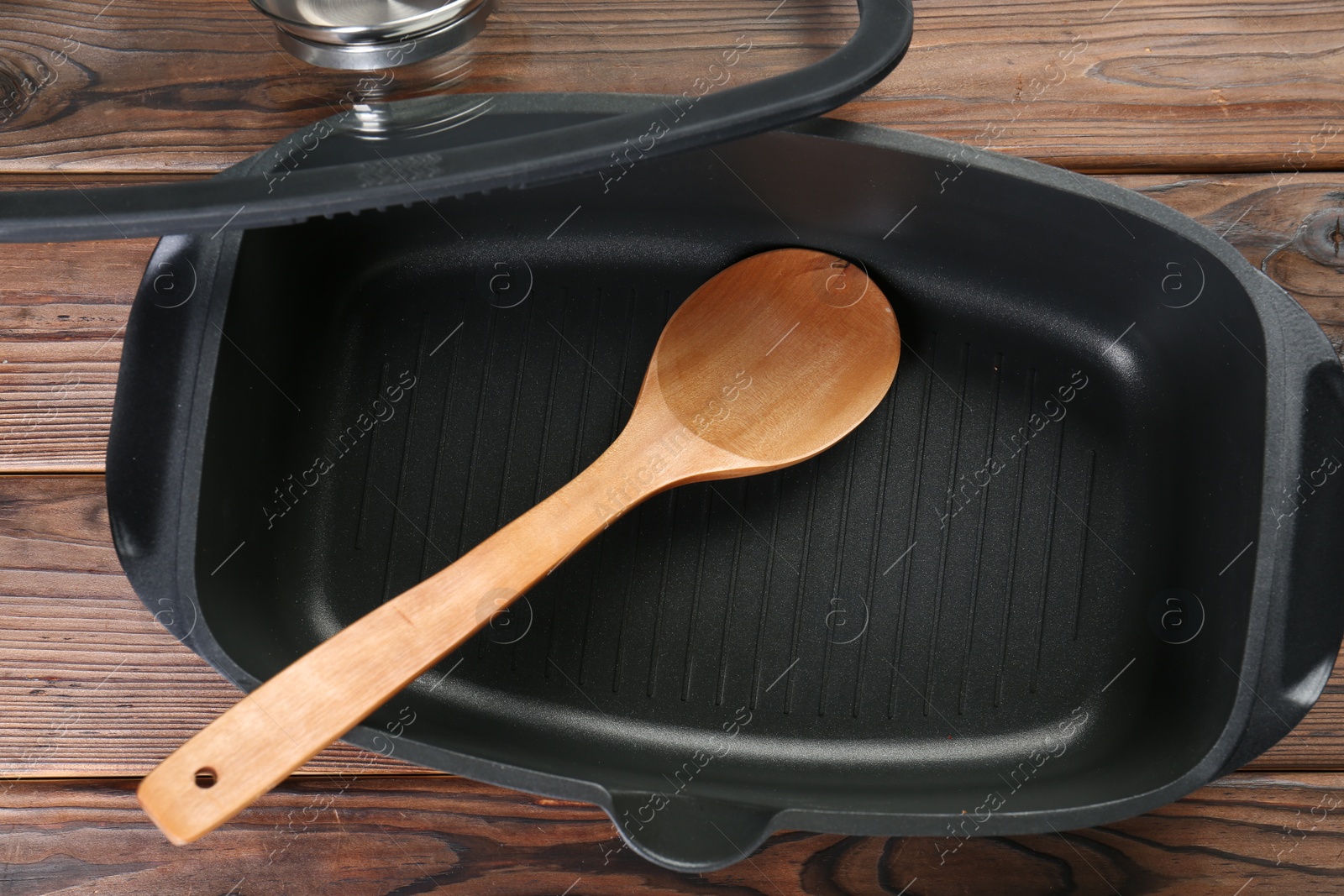 Photo of Black pot and spoon on wooden table, flat lay