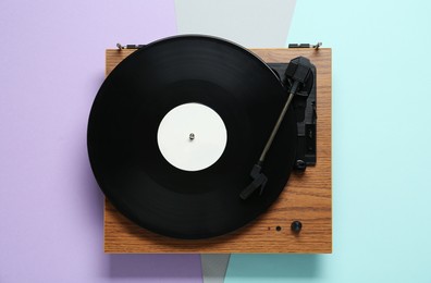 Turntable with vinyl record on color background, top view