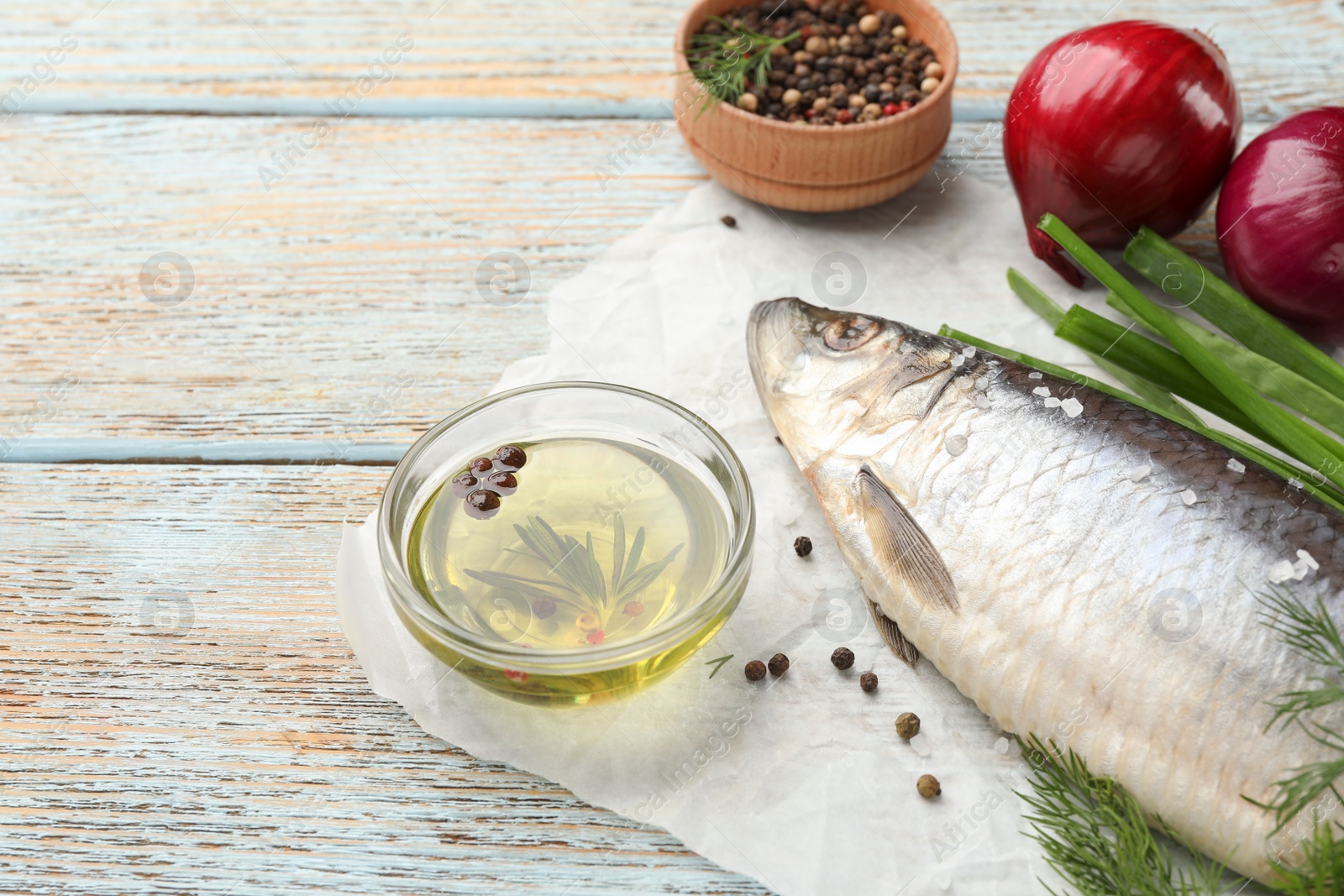 Photo of Delicious salted herring and ingredients on light blue wooden table