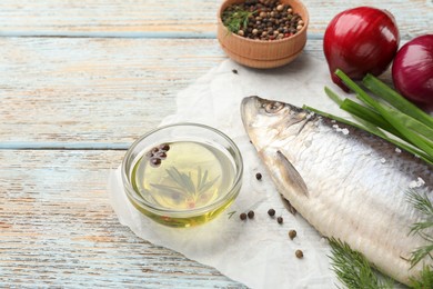 Photo of Delicious salted herring and ingredients on light blue wooden table