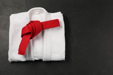 Photo of Red karate belt and white kimono on gray background, top view. Space for text