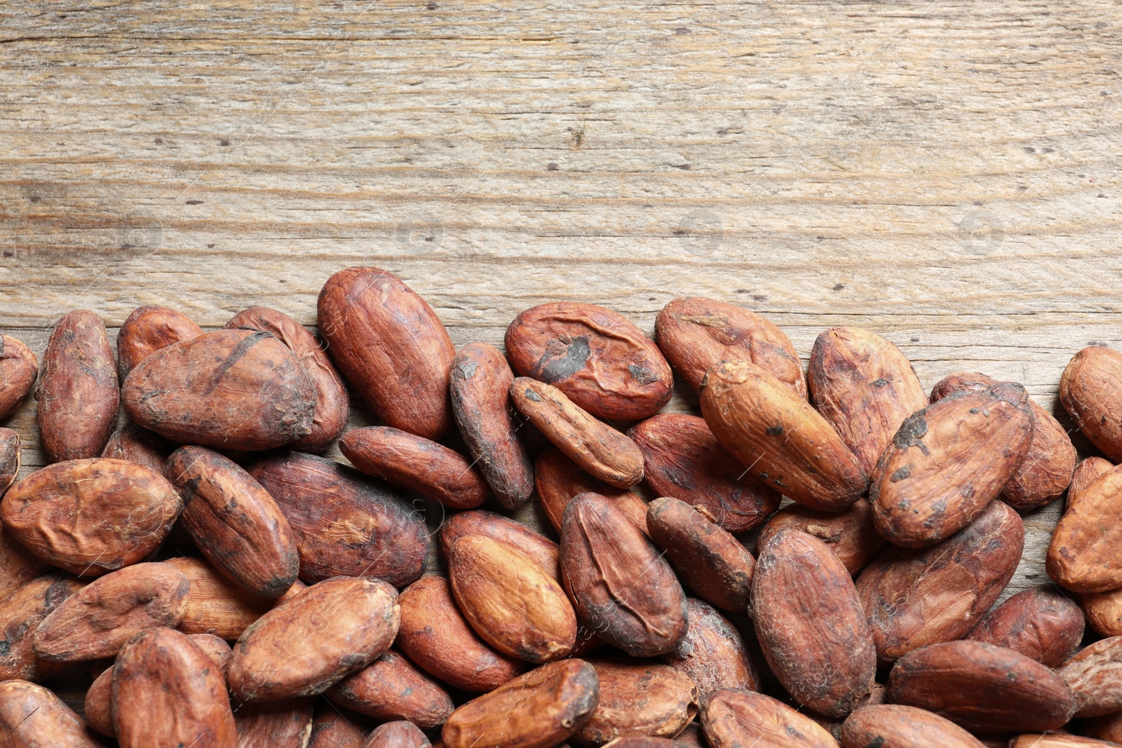 Photo of Tasty cocoa beans on wooden table, top view. Space for text