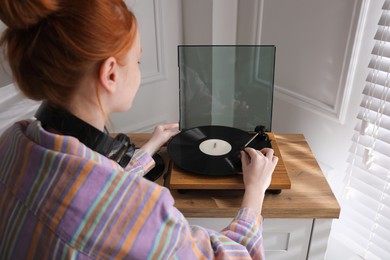 Beautiful young woman using turntable at home