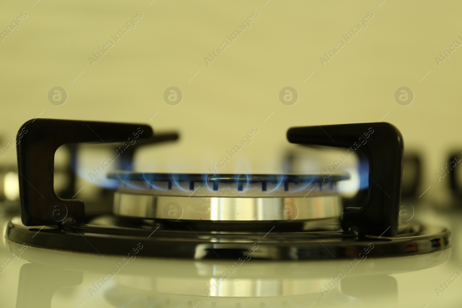 Photo of Gas burner of modern stove with burning blue flame, closeup